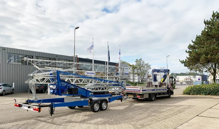 Transport van een mobiele Vicario bouwkraan op een aanhanger, getrokken door een vrachtwagen van Bouwma Bouwmachines op het bedrijfsterrein.